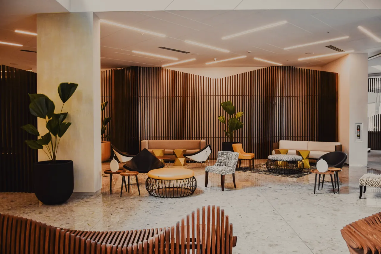 A residents’ lobby lounge: terrazzo floor, timber-slat wall, low sofas