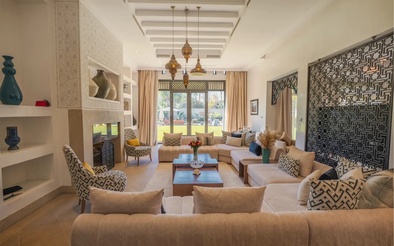 A majlis lounge: a long low U of cream sofas around timber tables