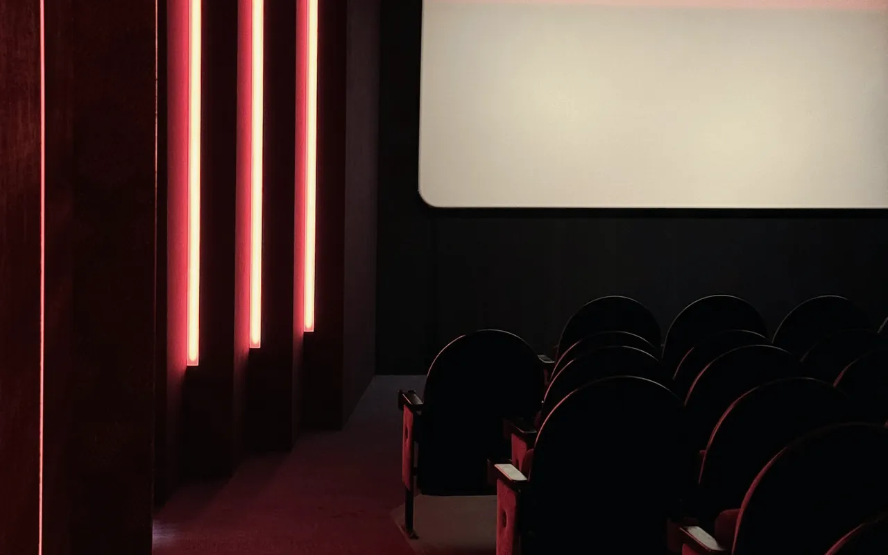 A small screening room: a screen and rows of dark velvet seats